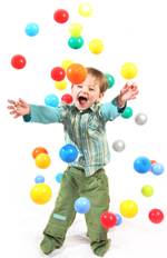 A happy kid playing with colorful balls.